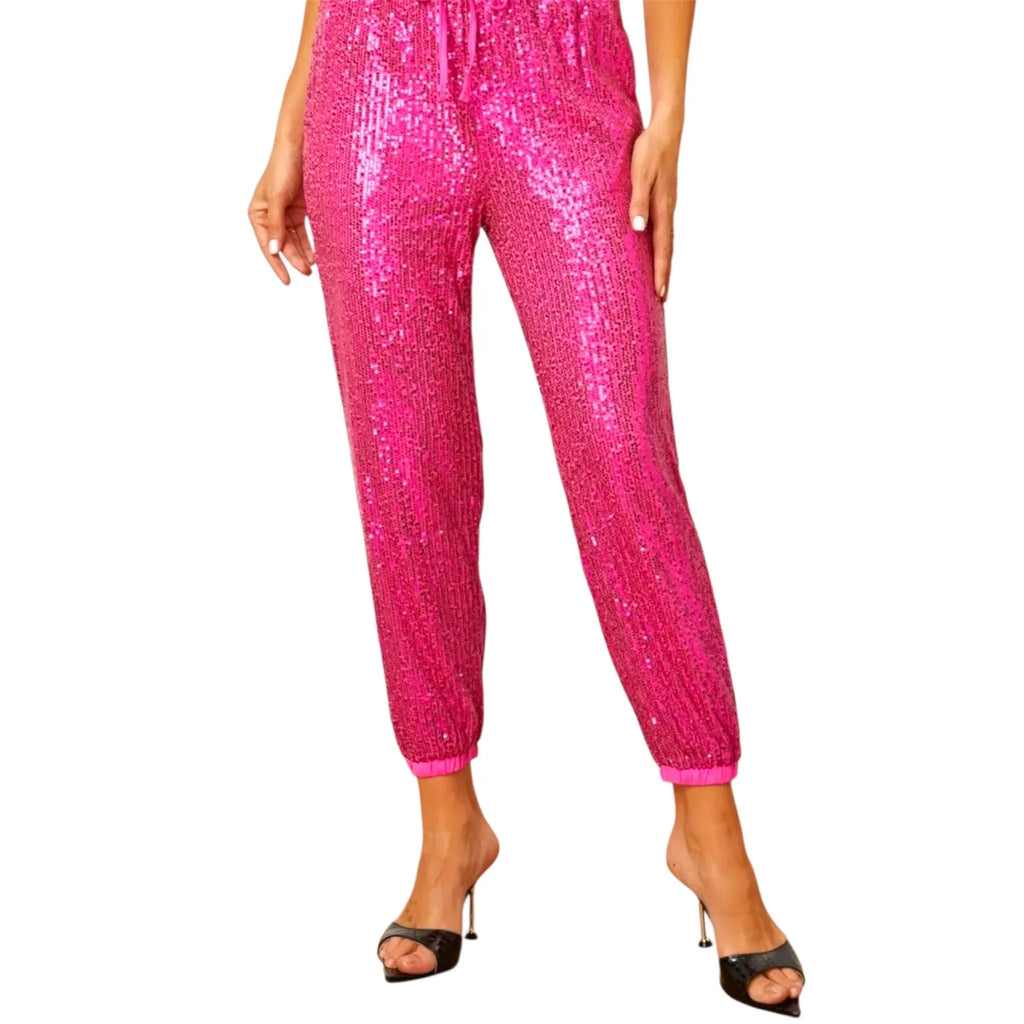 Woman wearing hot pink sequin jogger pants with elastic cuffs and drawstring waist, paired with black high heel sandals – Jewelry Bubble bottoms collection hero image